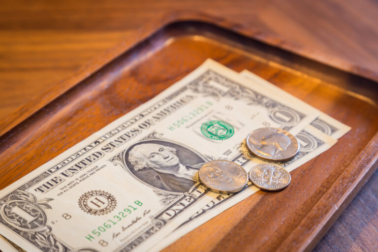 Cash tips left on a tray at a restaurant table, representing American tipping culture.